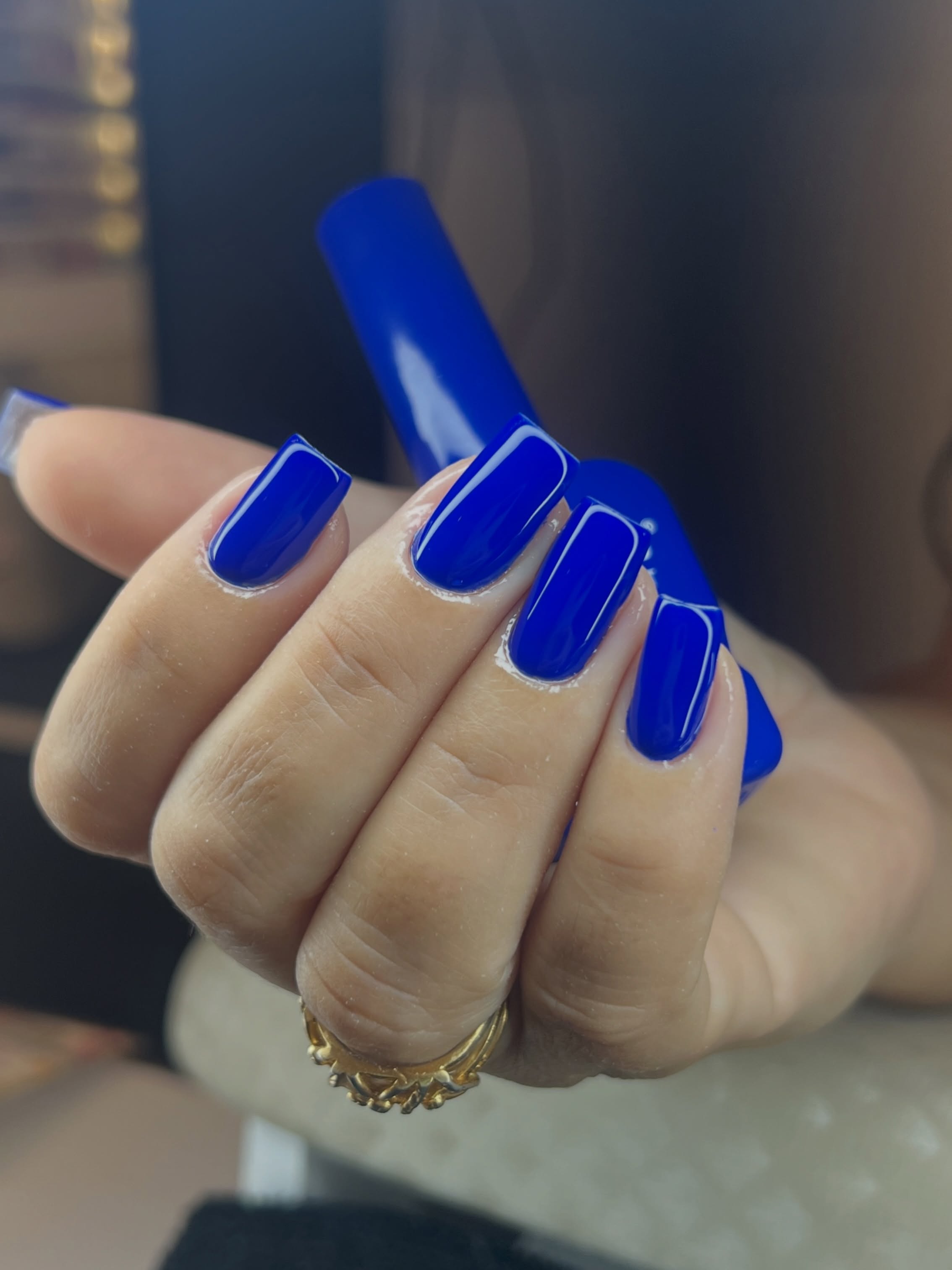 Unhas alongadas azul intenso com acabamento brilhante e formato quadrado de cantos suaves.