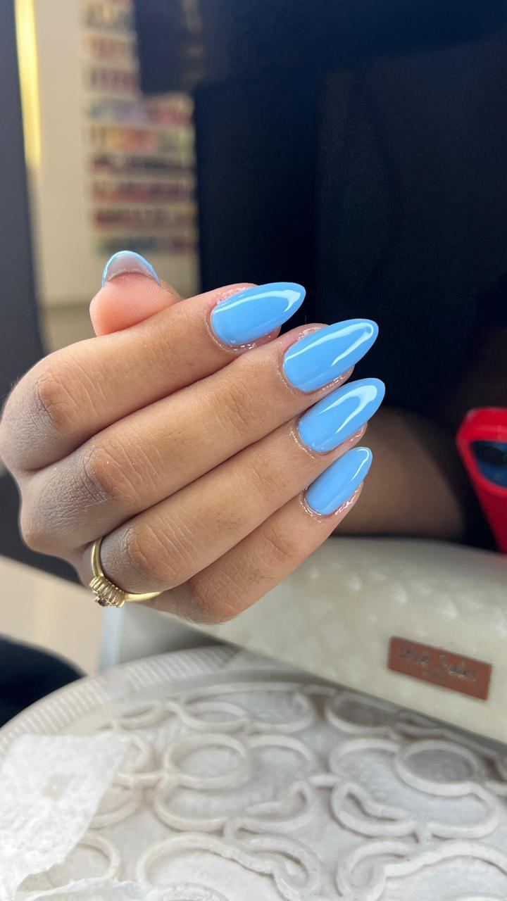 Unhas alongadas em formato amendoado, esmaltadas em azul claro brilhante com acabamento uniforme e elegante.